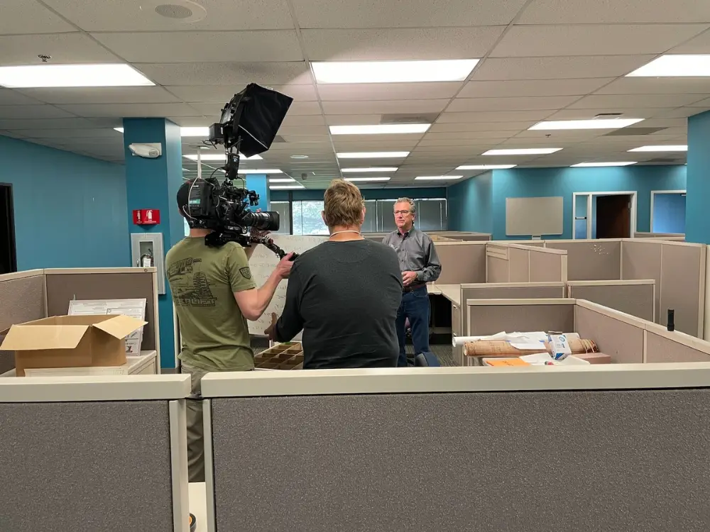 Professional video production crew filming a corporate interview in a Plymouth, Michigan office